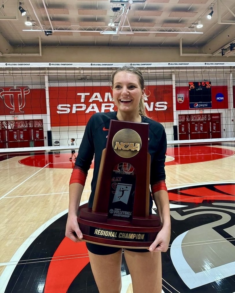 Tess holding an NCAA regional championship trophy