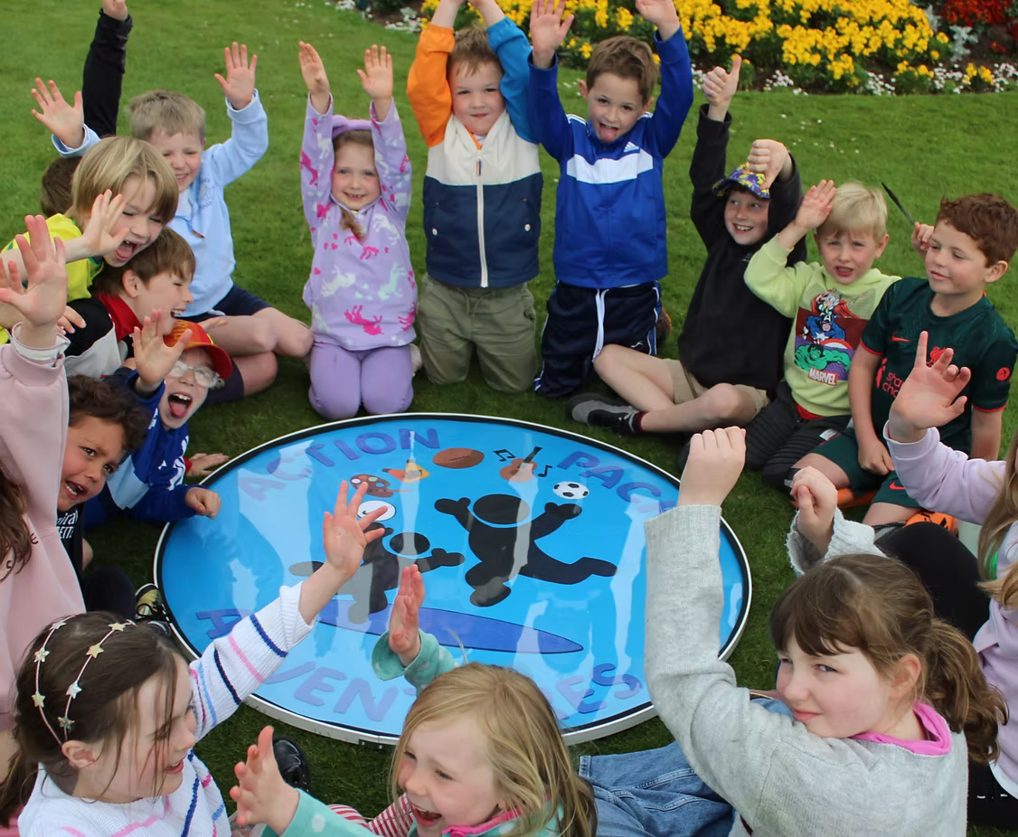 Children cheering with hands up around the Action Packed Adventures logo